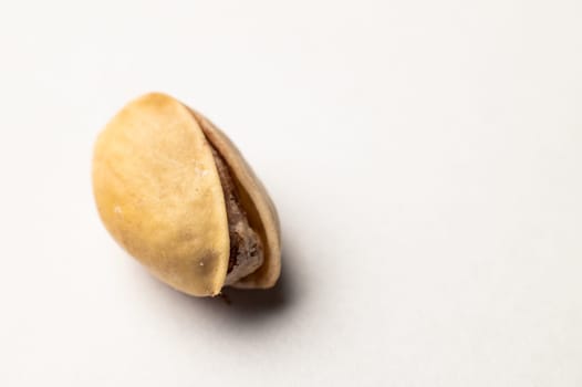 One pistachio nut on a white background, close-up.