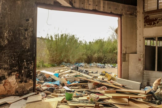 Delve into the haunting landscape of urban decay and environmental degradation with this striking image of a mountain of trash in an abandoned factory.