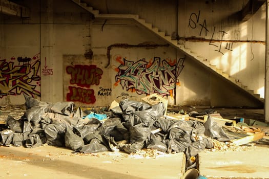 Peer into the gritty underbelly of urban life with this arresting image capturing piles of trash bags amidst the desolation of abandoned city streets.