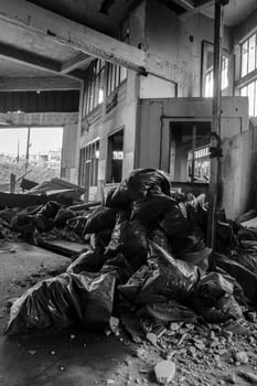 Peer into the gritty underbelly of urban life with this arresting image capturing piles of trash bags amidst the desolation of abandoned city streets.