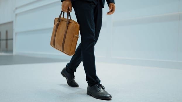 Closeup of professional business man leg walking while holding bag. Cropped image of project manager focus on leg. Traveling, moving, journey, walking, getting a new position, job changing. Exultant.