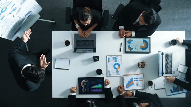 Top down aerial view of professional boss invites project manager to explain about marketing plan at white board while giving a handshake. Group of diverse investor listen presentation. Directorate.