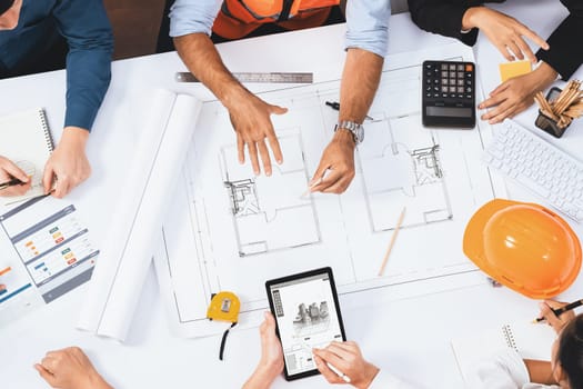 Top view banner of diverse group of civil engineer and client working together on architectural project, reviewing construction plan and building blueprint at meeting table. Prudent