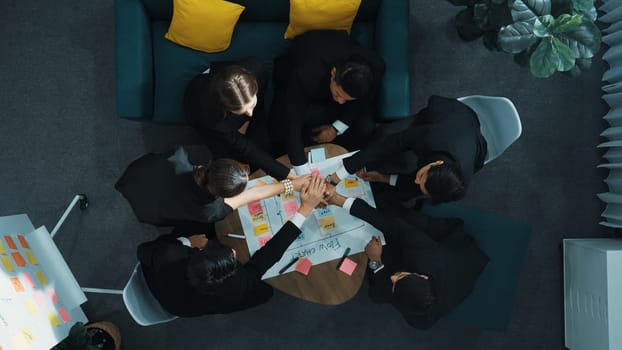 Top view of business people putting hands together and clapping hands to celebrate successful project while using kanban task board to manage time. Startup team stacking hands together. Directorate.