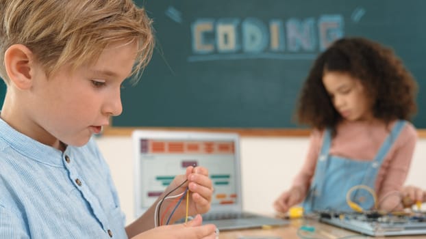 Girl standing while fixing electronic board by using screwdriver. American student and happy caucasian boy working together to inspect electric system. Curious children working on board. Pedagogy.