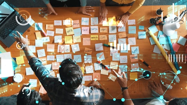 Top down view of business team with casual outfit looking laptop screen and sharing idea. Aerial view of manager works and checking color palette at table with statistic graph holographic. Symposium.