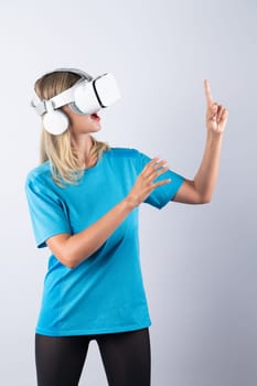 Girl pointing or spinning basketball while using VR glasses. Caucasian woman flexing while wearing casual shirt and visual reality goggles and standing at pink background. Innovation. Contraption.