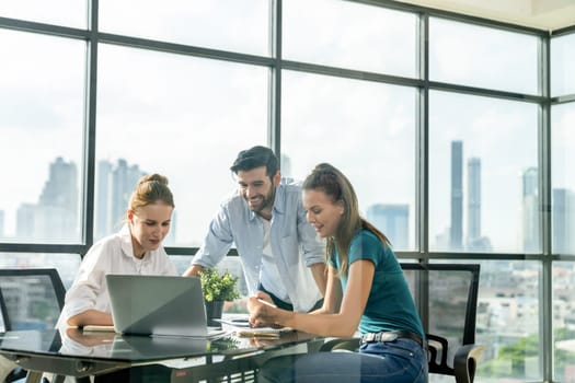 Group of diverse profession business people pointing at laptop displayed idea. Portrait of business team show marketing strategy present by laptop with statistic document scatter on table. Tracery.