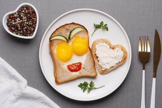 Valentine's Day breakfast with egg heart shaped and toast bread on grey background. Top view. Copy space.