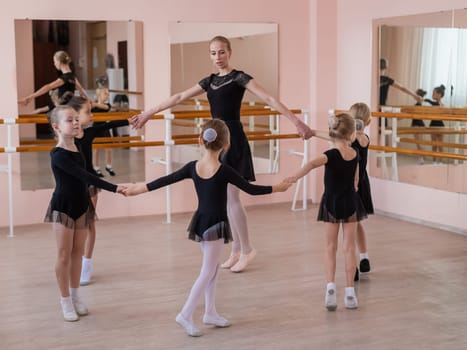 Children's ballet school. Caucasian woman teaching ballet to little girls
