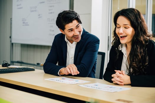 Businesspeople at an office desk, working together and planning. Their cooperation is reflected in the discussion, paperwork, and analysis of financial graphs for business success.