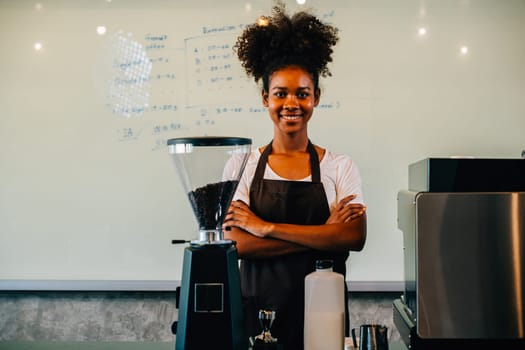 Portrait of a confident black woman owner standing at cafe counter. Successful businesswoman in uniform providing excellent service smiling with satisfaction. Inside a small business cafe