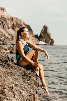 Woman beach vacation photo. A happy tourist in a blue bikini enjoying the scenic view of the sea and volcanic mountains while taking pictures to capture the memories of her travel adventure