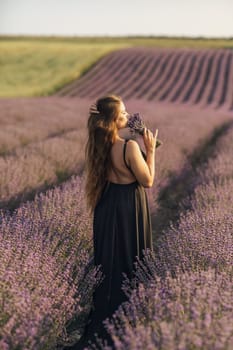 woman stands in a lavender field of purple flowers, holding a bouquet of flowers. The scene is serene and peaceful, with the woman taking a moment to enjoy the beauty of nature