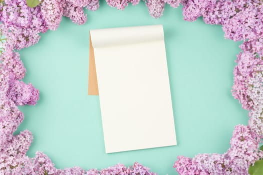 Open notebook with flowers on isolated cyan background. Open craft album. Top view.