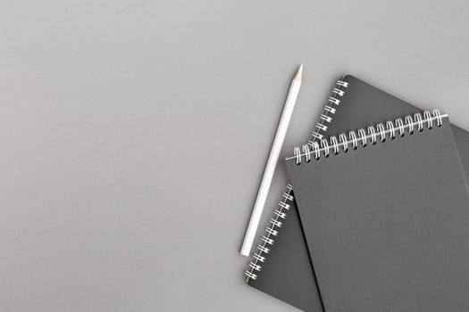 Spiral notebook with black paper sheets and white pencile on gray isolated background. Top view close up.