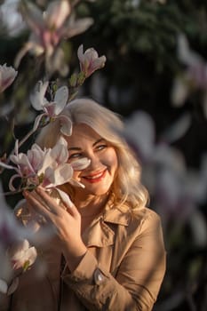 Magnolia flowers woman. A woman is holding a magnolia flower in her hand and standing in front of a tree. Concept of serenity and beauty, as the woman is surrounded by nature and the flower adds a touch of color