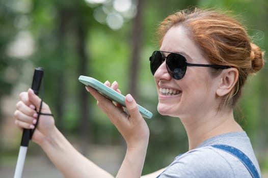 Happy blind woman sitting on bench and talking on smartphone