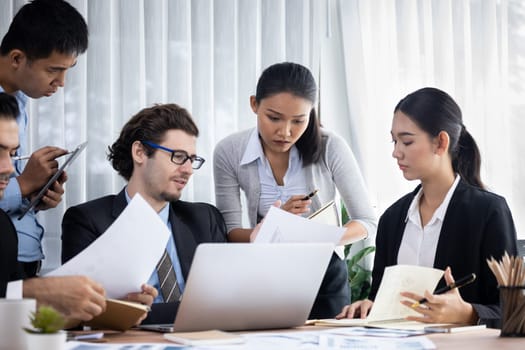 Diverse group of business analyst team analyzing financial data report paper on office table. Chart and graph dashboard by business intelligence analysis for strategic marketing planning Meticulous