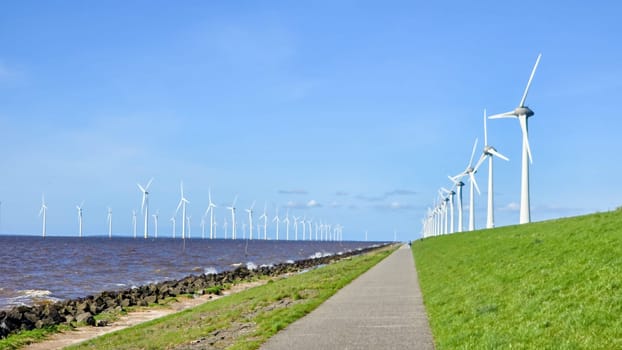 offshore windmill park and a blue sky, windmill park in the ocean. Netherlands Europe. windmill turbines in the Noordoostpolder Flevoland, road on a Dutch dike