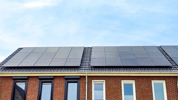 Newly built houses with black solar panels on the roof against a sunny sky Close up of new building with black solar panels. Zonnepanelen, Zonne energie, Translation: Solar panel, Sun Energy