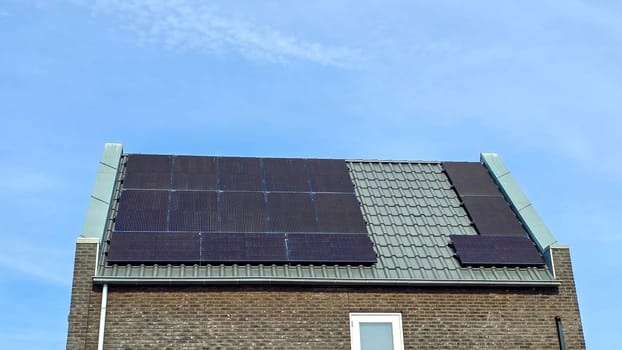 modern family houses with black solar panels on the roof against a sunny sky Close up of new building with black solar panels. Zonnepanelen, Zonne energie, Translation: Solar panel, Sun Energy