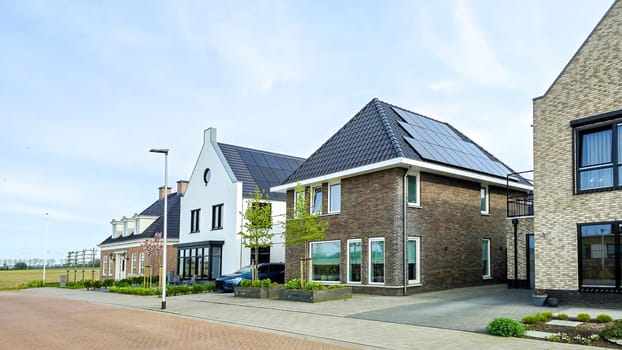 street of Newly built houses with black solar panels on the roof against a sunny sky Close up of new building with black solar panels. Zonnepanelen, Zonne energie, Translation: Solar panel, Sun Energy