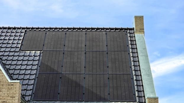 Dutch Suburban area with black solar panels on the roof against a sunny sky Close up of new house with black solar panels. Zonnepanelen, Zonne energie, Translation: Solar panel, Sun Energy