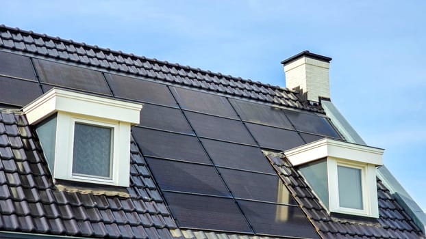 Dutch Suburban area with New houses with black solar panels on the roof , Close up of new building with black solar panels. Zonnepanelen, Zonne energie, Translation: Solar panel, Sun Energy
