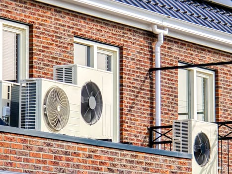 close up of an air source heat pump unit installed outdoors at a modern home with solar panels in the Netherlands. Zonnepanelen, warmte pomp, Translation: Solar panel, Heat pump