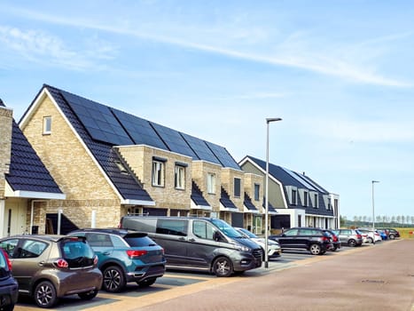 Dutch family houses with solar panels on the roof against a sunny sky. Zonnepanelen, Zonne energie, Translation: Solar panel, Sun Energy, Dutch Suburban area with modern family houses,
