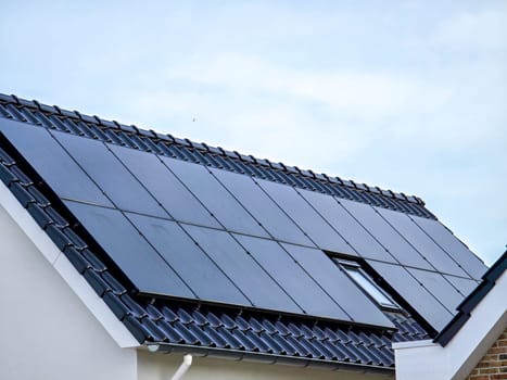 black solar panels on the roof against a sunny sky Close up of new house with black solar panels. Zonnepanelen, Zonne energie, Translation: Solar panel, Sun Energy, Suburban area