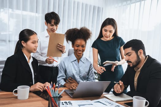 Multiracial analyst team use BI dashboard data to analyze financial report on meeting table. Group of diverse business people utilize data analysis by FIntech for success business marketing. Concord