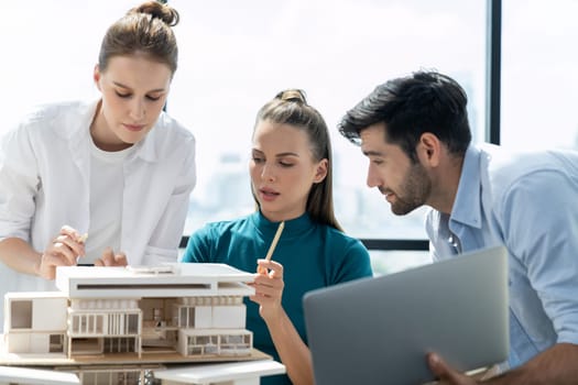 Portrait of skilled architect holding laptop while present idea to engineer team. Group of businesspeople brainstorm and analysis building construction. Civil engineering, working together. Tracery.