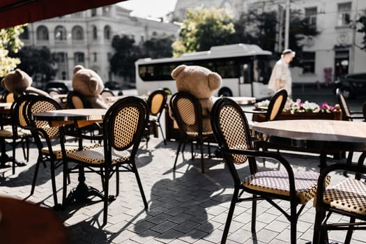 A restaurant with a lot of chairs and tables. There are two teddy bears on the tables