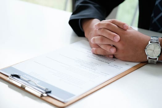 Close-up of a businessman's hands carefully examining a resume, focusing on qualifications for a job candidate.