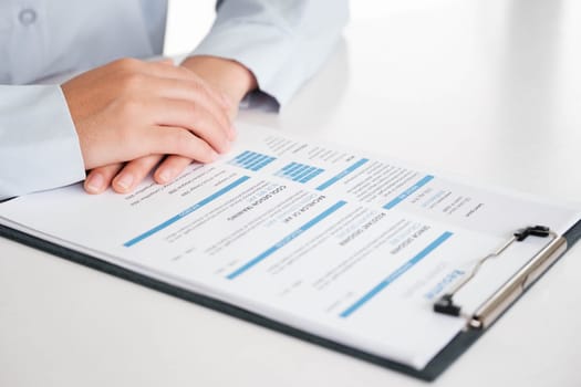 Close-up of a businessman's hands carefully examining a resume, focusing on qualifications for a job candidate.