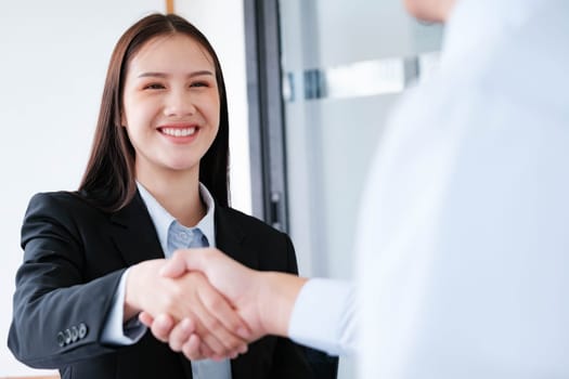 A young businesswoman smiles while shaking hands, making a positive impression during a professional meeting.