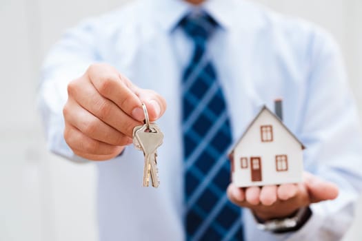 Real Estate Agent Presenting House Keys and Model Home, Emphasizing New Homeownership and the Joy of Real Estate Transactions