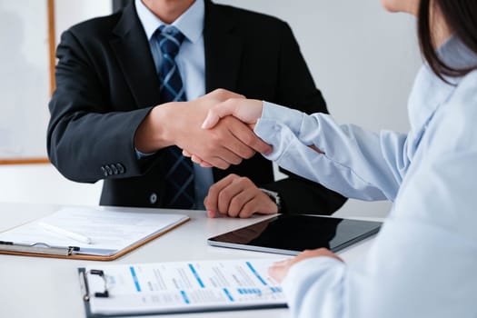 A job interviewer and applicant seal the interview process with a firm handshake, indicating a positive outcome.