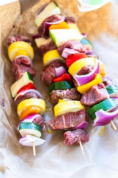 Raw skewers with beef and fresh veggies, wrapped in butcher brown paper, await grilling.