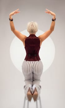 studio photo of a sexy girl in a suit sitting with her back on a bar stool on a light background