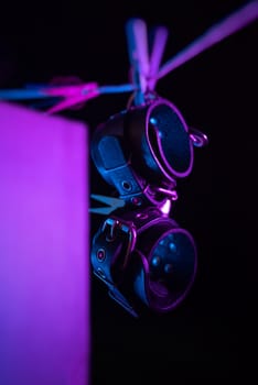 bdsm leather handcuffs hanging on a clothesline in neon light on black background