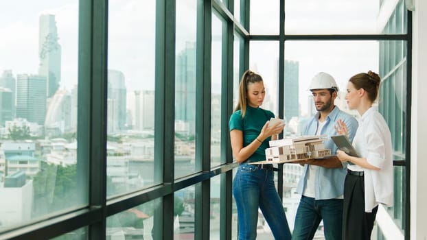 Skilled engineer holds house model and explain about house construction to skilled manager. Group of interior designer inspect architectural model. Working together, Civil engineering. Tracery