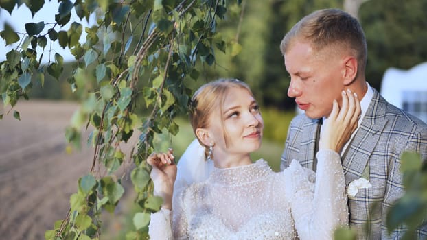 The bride and groom enjoy each other by the branches of a birch tree