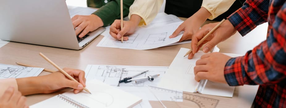 Skilled architect team using architectural equipment during colleague discussion about building design at meeting table with blueprint scatter around. Closeup. Focus on hand. Delineation.