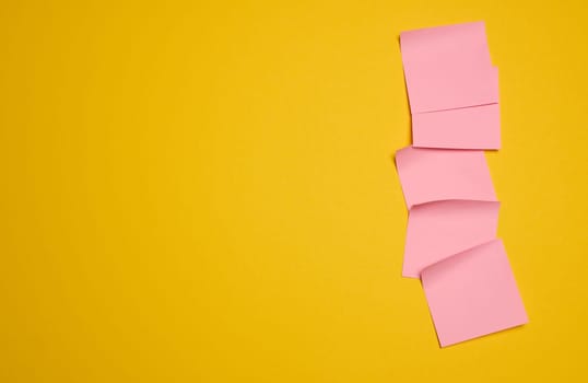 Pink square sticks are glued to the yellow background, copy space