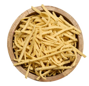 Raw wheat noodles in wooden bowl on isolated background, top view