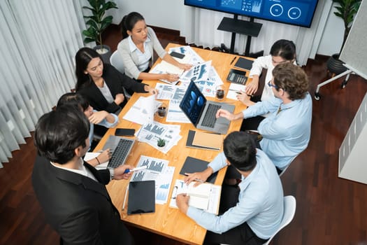 Diverse group of business analyst team analyzing financial data report. Finance data analysis chart and graph dashboard show on TV screen in meeting room for strategic marketing planning. Habiliment