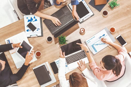 Top view of businessman executive in group meeting with other businessmen and businesswomen in modern office with laptop computer, coffee and document on table. People corporate business team uds